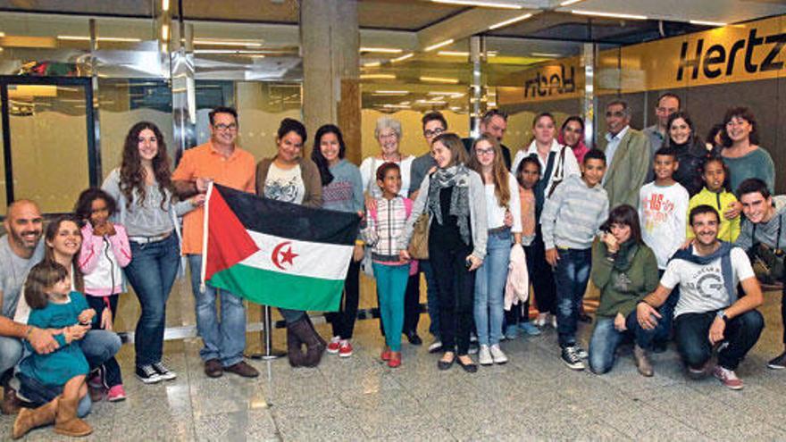 Imagen de grupo de las familias mallorquinas con los niños que acogerán en sus domicilios y la bandera de su país, el Sahara.