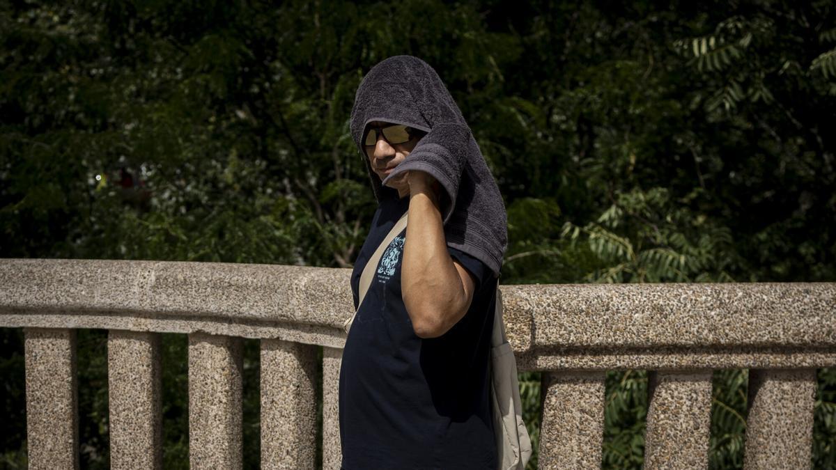 Un hombre se cubre del sol con una toalla durante la ola de calor en Zaragoza