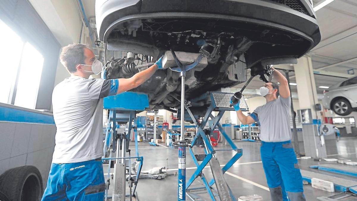 Dos mecánicos revisan un coche en un taller, una de las actividades con alta rotación de empleo.