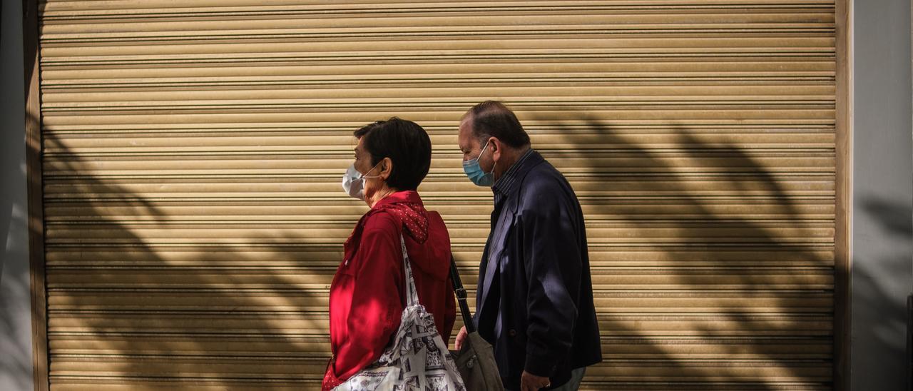 Dos personas pasean en Santa Cruz de Tenerife con mascarilla para evitar contagios de covid.