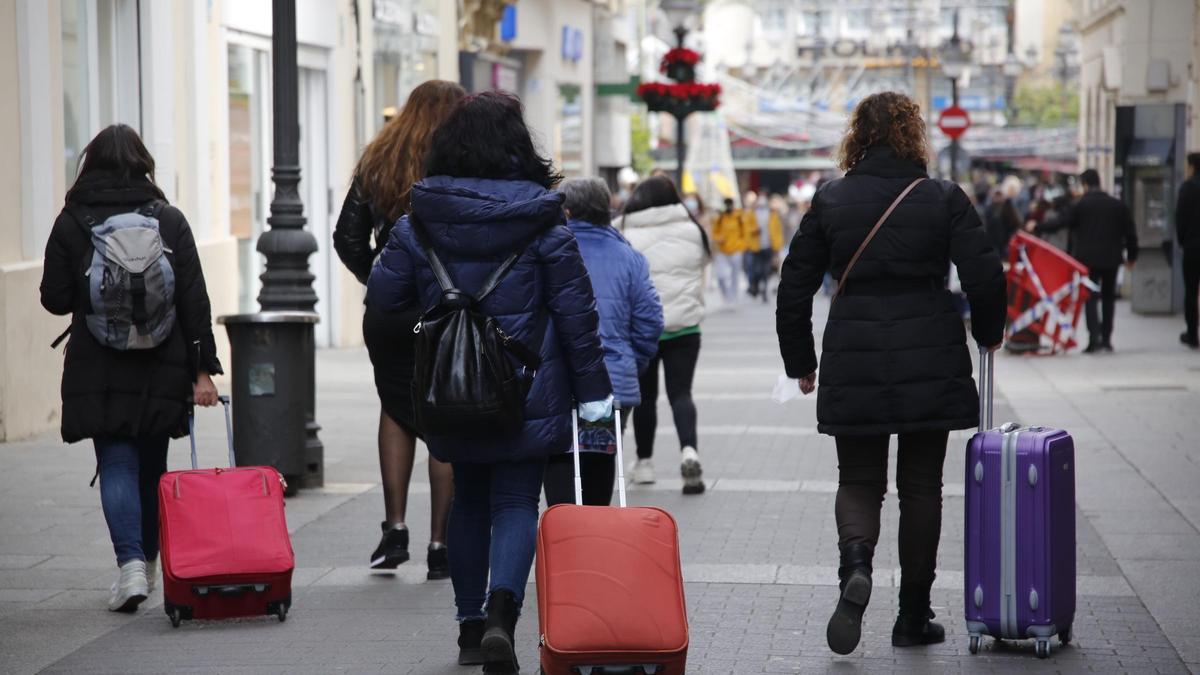 Viajeros pasean por la calle Gondomar de Córdoba con sus maletas.