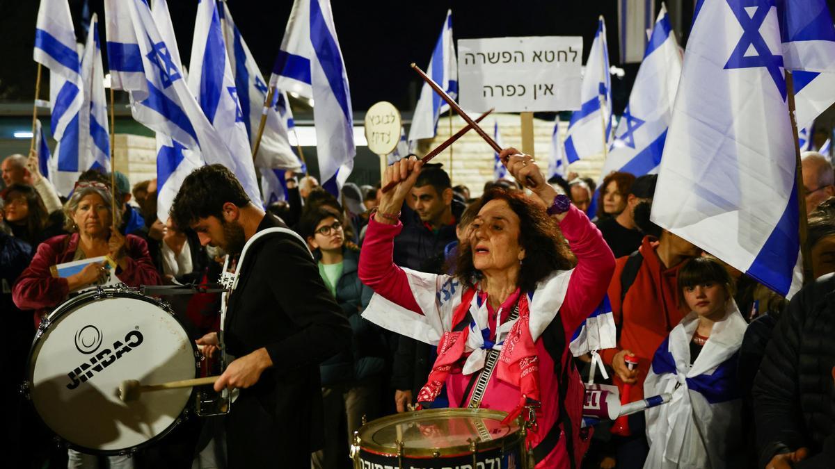 La gente sostiene banderas israelíes durante una manifestación mientras el gobierno de coalición nacionalista del primer ministro israelí, Benjamin Netanyahu, presiona con su polémica reforma judicial.