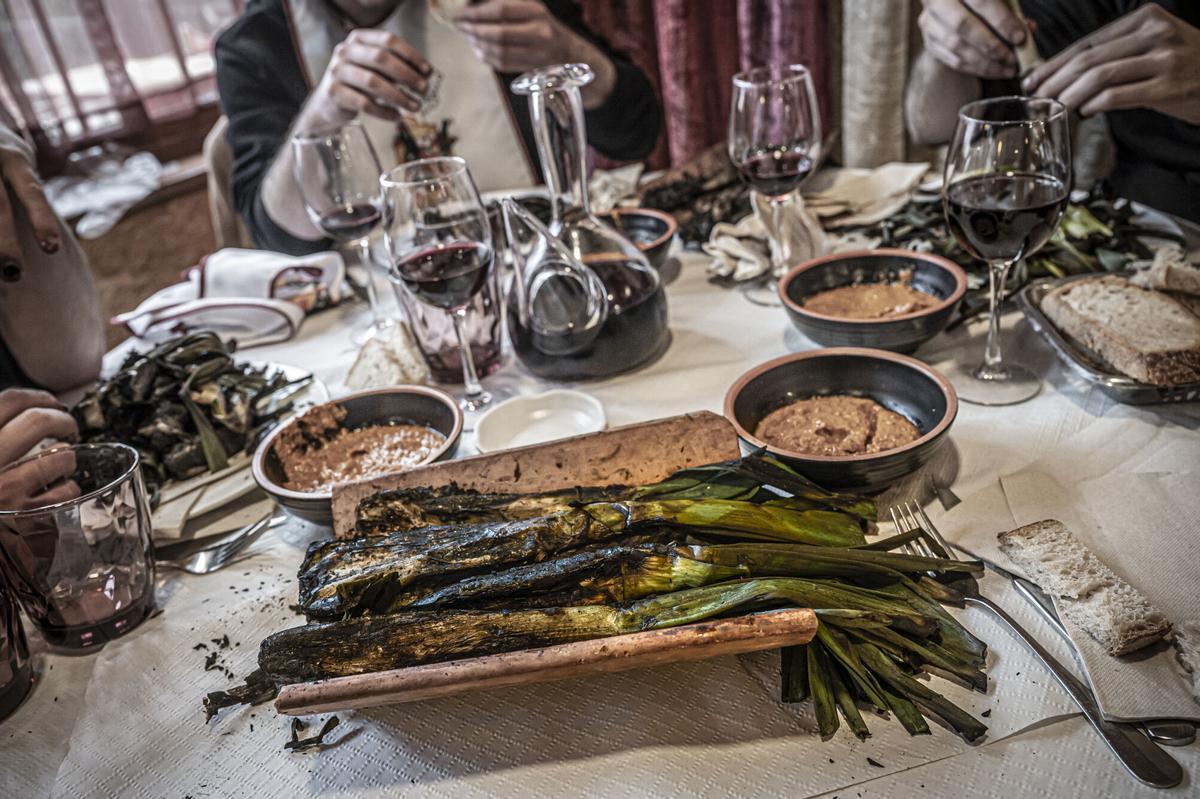 Calçots damunt d'una teula amb salsa de calçots i vi.