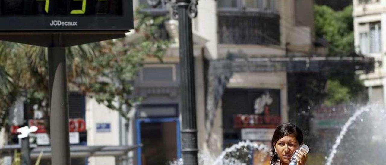 Una joven se refresca con agua a 45º y en la cercanía de una fuente, durante la ola de calor en España. //Efe