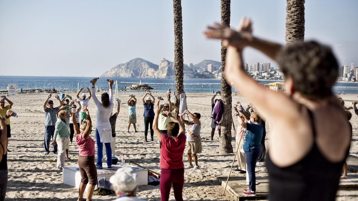 Un grupo de personas mayores hace gimnasia en la playa de Poniente de Benidorm, en una imagen anterior a la pandemia.