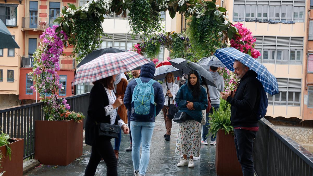 Un dels ponts de Girona amb gent passejant amb paraigües. | GERARD VILÀ