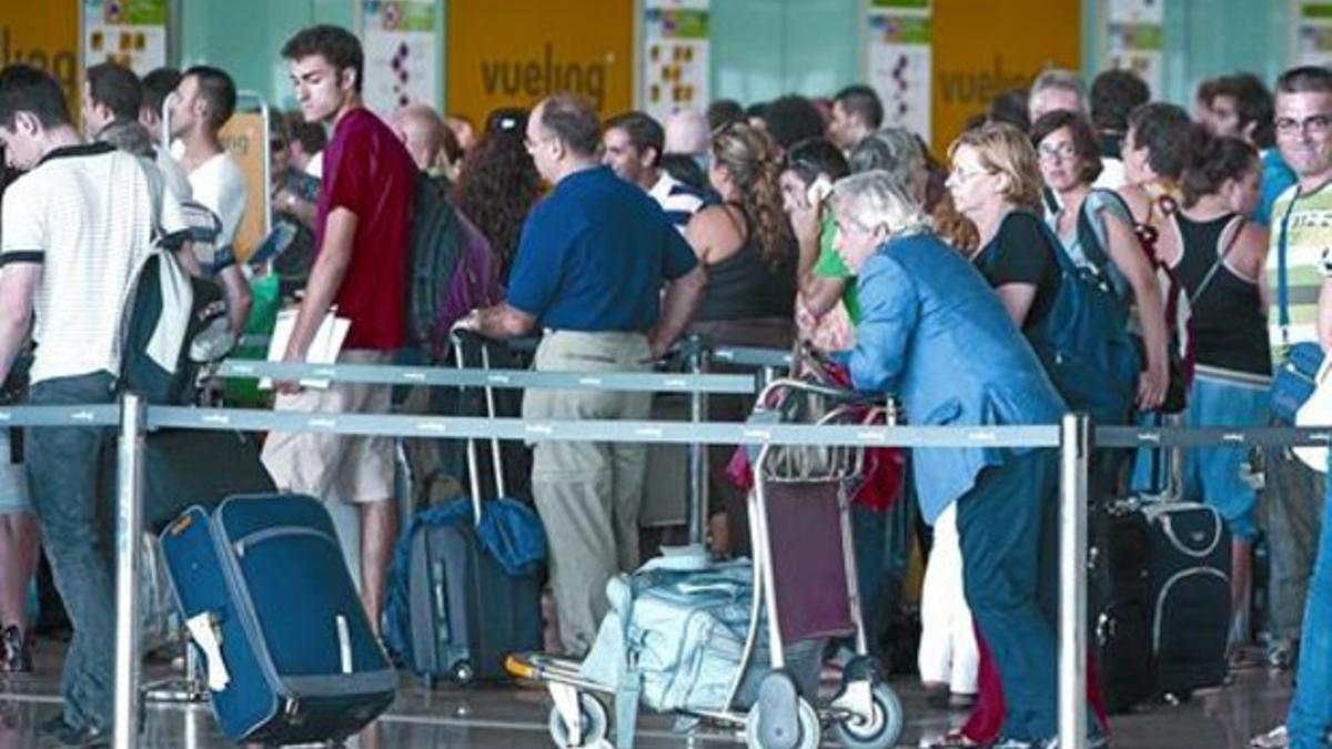 Viajeros hacen cola ante los mostradores de facturación de la T-1 del aeropuerto de El Prat, ayer.