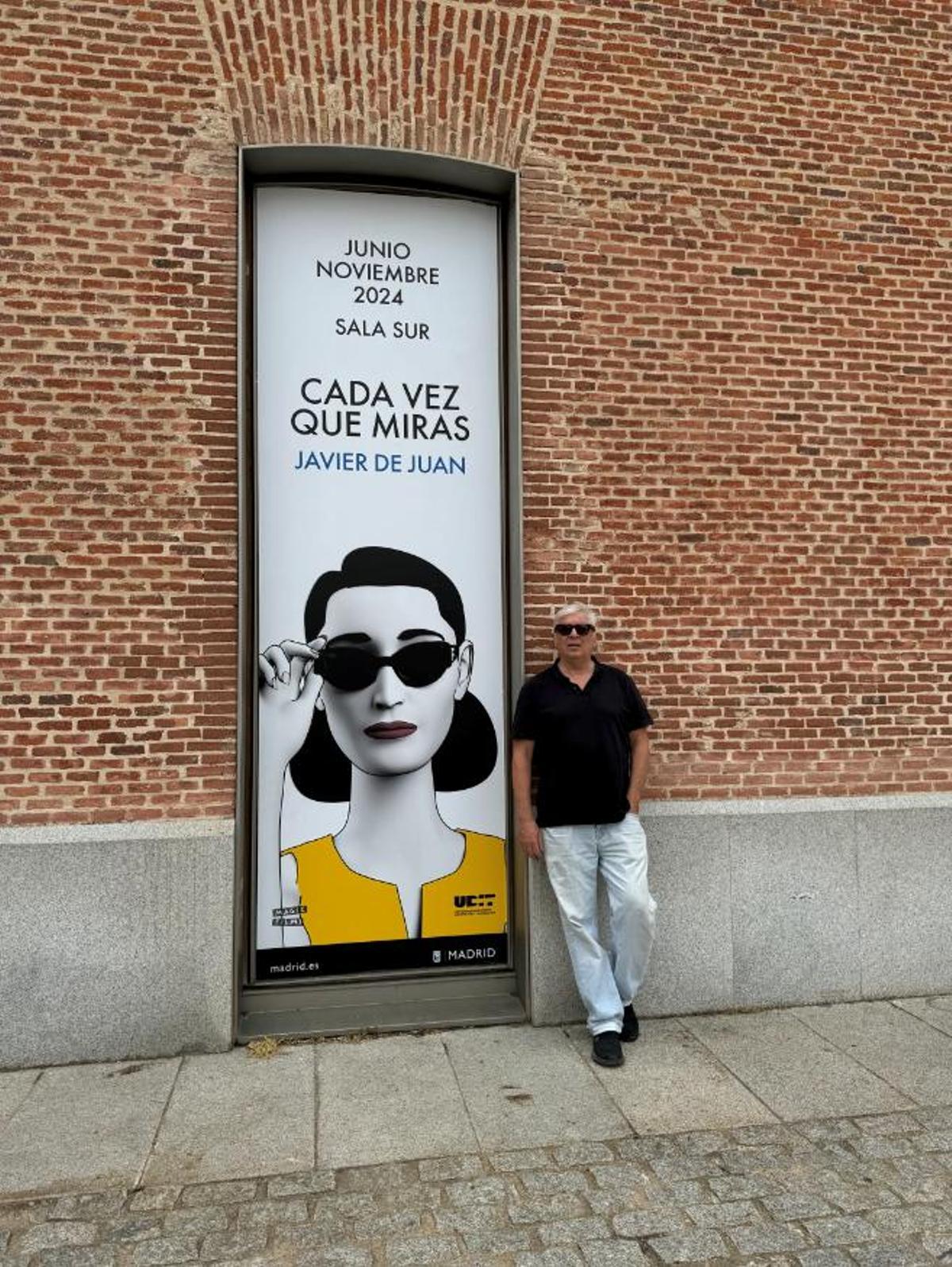 El artista, junto al cartel que anuncia su muestra en Condeduque.