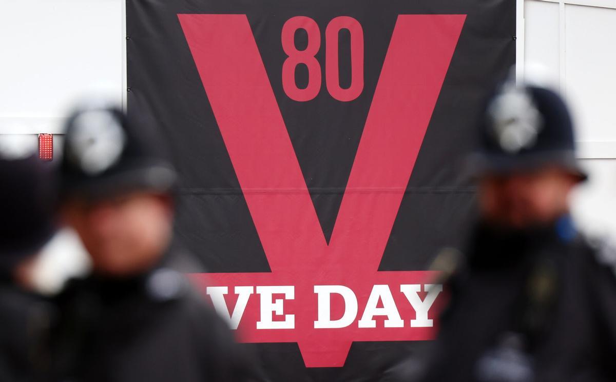 Policías británicos ante un cartel del Día de la Victoria antes del desfile militar para conmemorar el 80 aniversario del fin de la II Guerra Mundial, en Londres, el 5 de mayo de 2025. EFE/EPA/ANDY RAIN