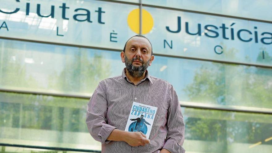El periodista Francesc Arabí muestra su libro frente a la Ciudad de la Justicia, impulsada por Zaplana e inaugurada por él en marzo de 2003.