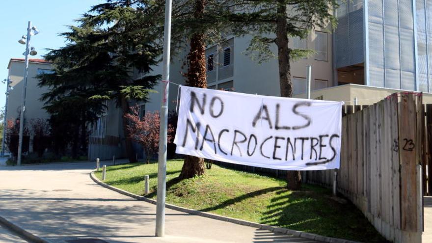 Imatge exterior del centre de la Misericòrdia de Girona -on anirà el nou centre d&#039;acollida- amb una pancarta en contra del &quot;macrocentre&quot;