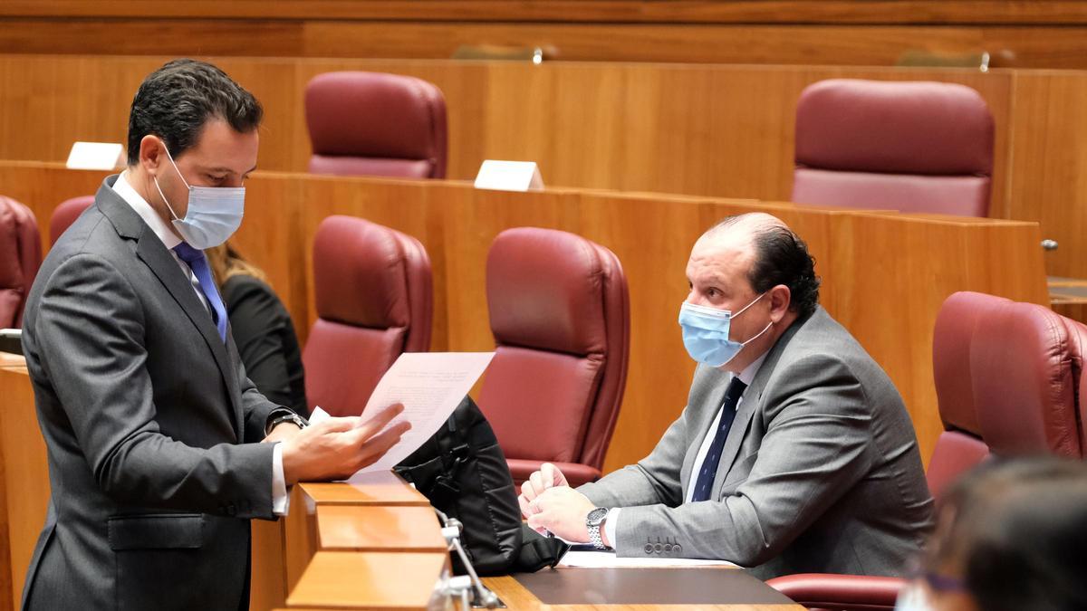 El portavoz del grupo popular, Raúl de la Hoz, conversa con el procurador, Pedro Antonio Heras, durante en Pleno de las Cortes.