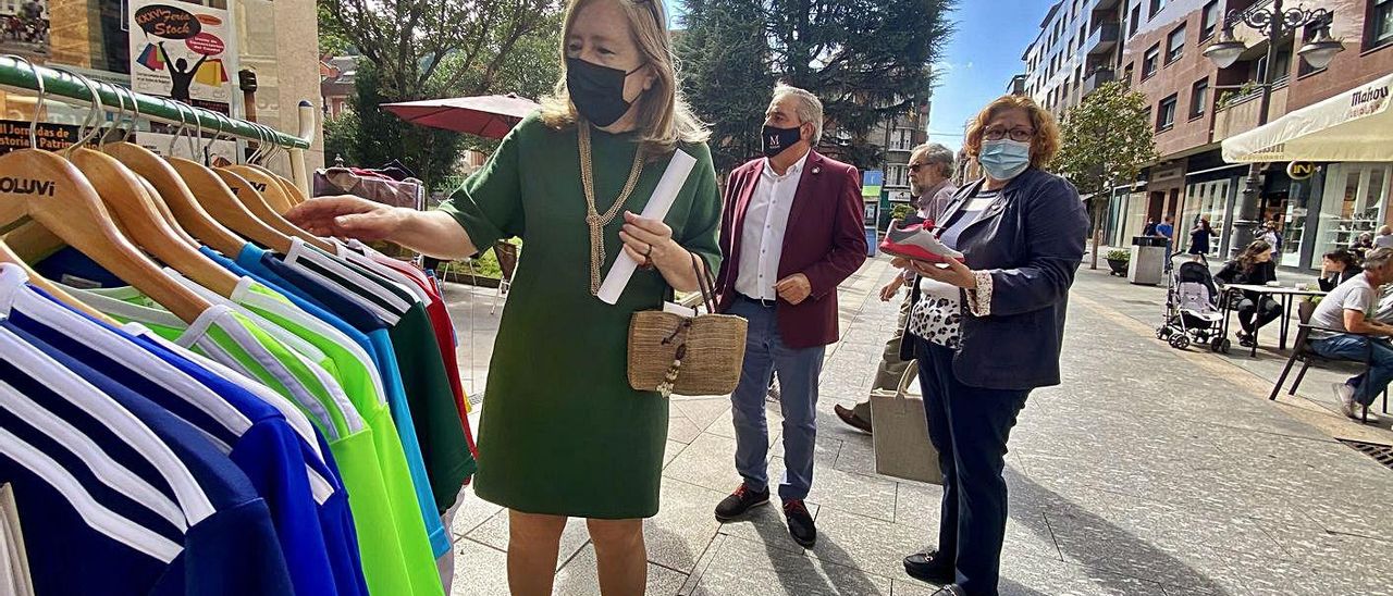 Dolores Olavarrieta, junto a un perchero de una tienda, con Gloria Muñoz y Aníbal Vázquez detrás. | C. M. B.