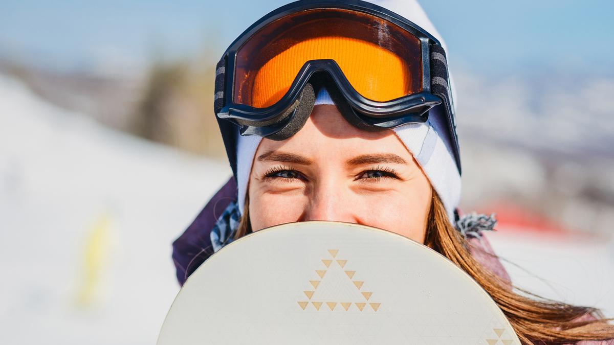 Chica en la nieve con tabla de snowboard