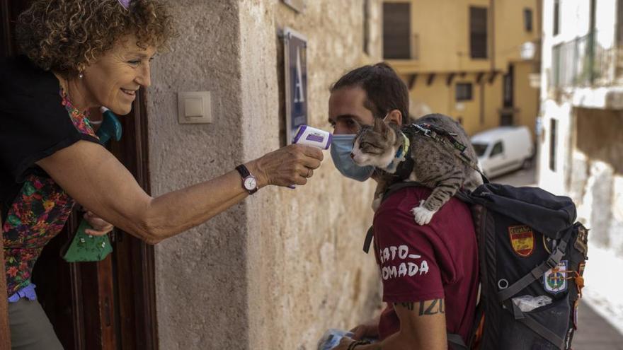 Marcelo Rodríguez, con su gato Osiris se someten a la prueba de temperatura antes de entrar al albergue de peregrinos de Zamora.