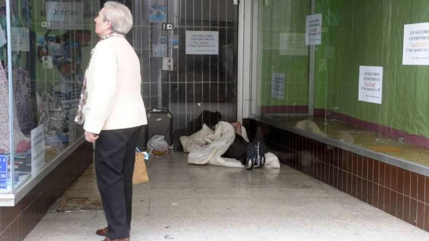 Imagen de una persona sin hogar en un soportal de la ciudad.