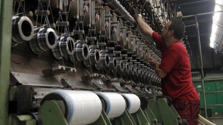 Un treballador comprova una màquina en una indústria tèxtil