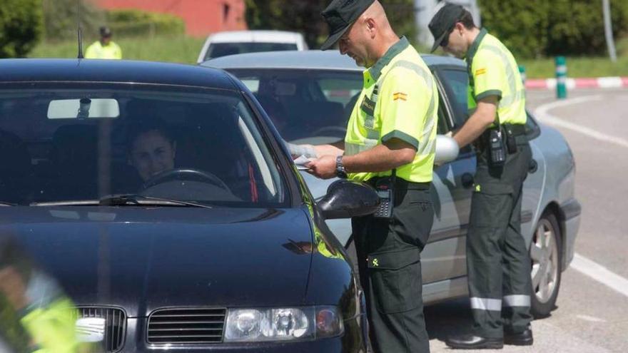 Dos agentes de la Guardia Civil, ayer, realizando un control de tráfico en la rotonda de La Pixarra de Oviedo, en una campaña de seguridad vial.