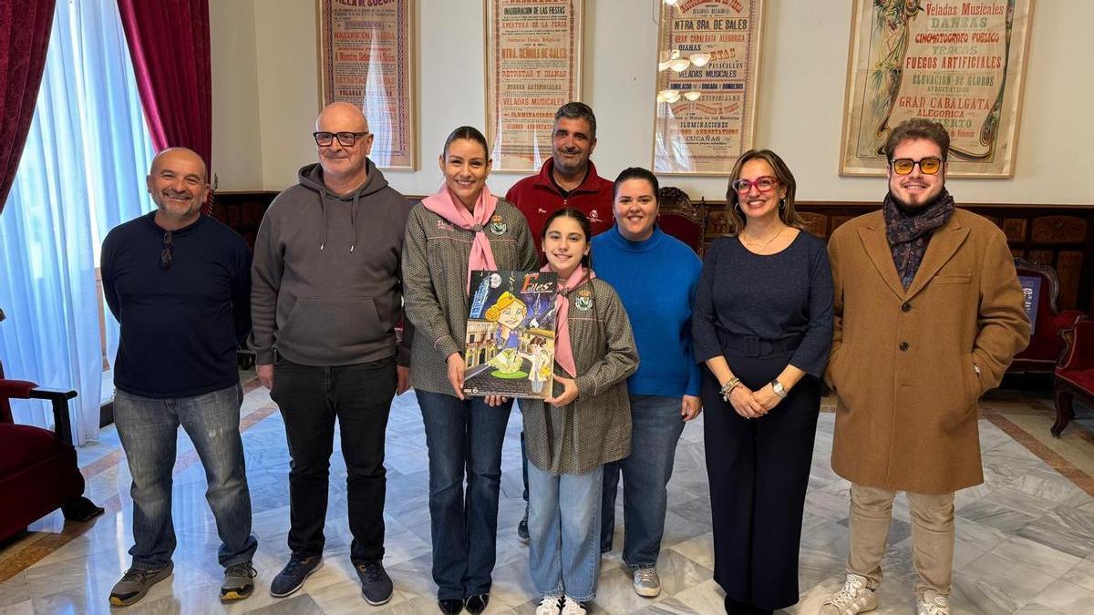 Las falleras mayores de Sueca muestran el cartel junto a los integrantes del jurado.