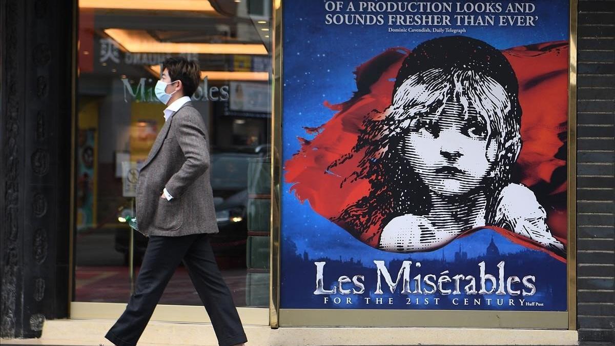 Un hombre con mascarilla pasa junto a la entrada de un teatro cerrado en Londres.