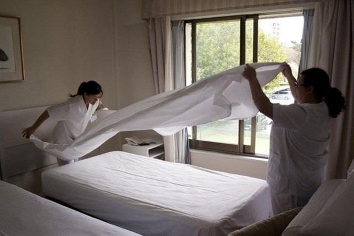Imagen de archivo de camareras de piso haciendo una cama.