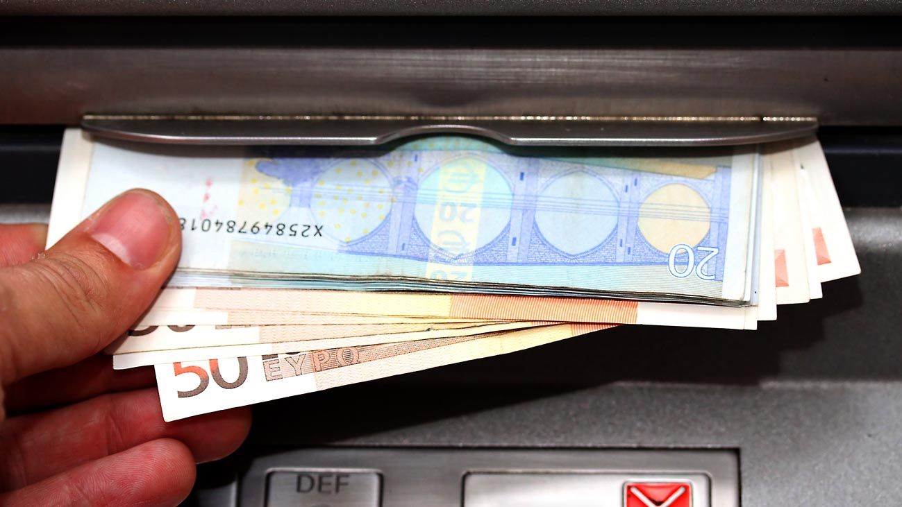 man takes money in EURO banknotes from an ATM