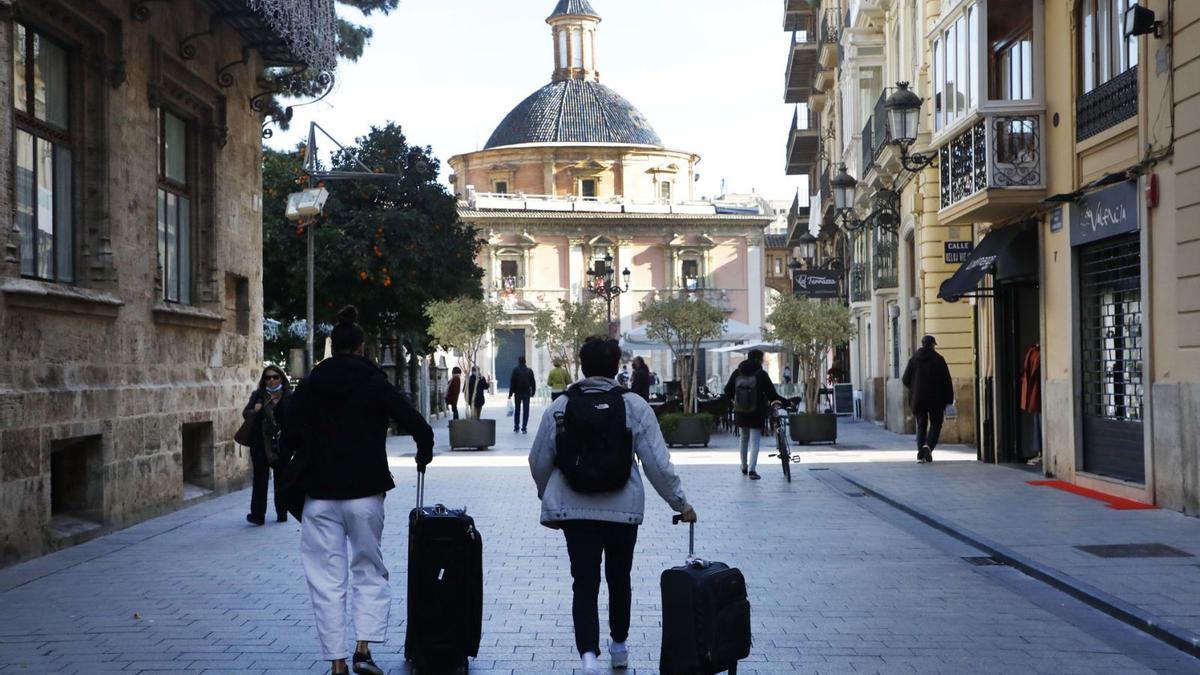 Dos turistas llegan al centro de València con sus maletas. | MIGUEL ÁNGEL MONTESINOS