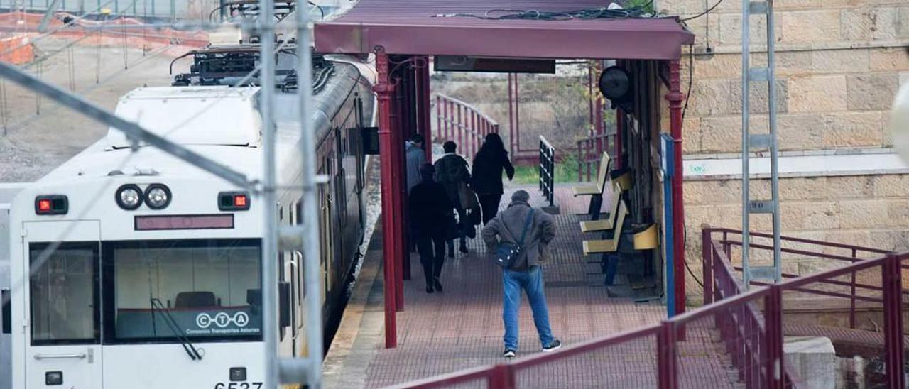 Varios viajeros junto al tren en la estación de Feve en Sama.