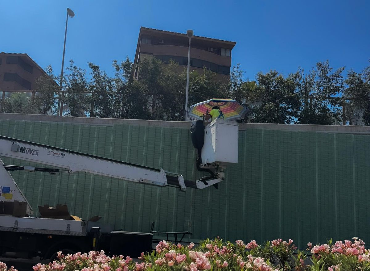 Un operario se protege del sol con una sombrilla en Alicante