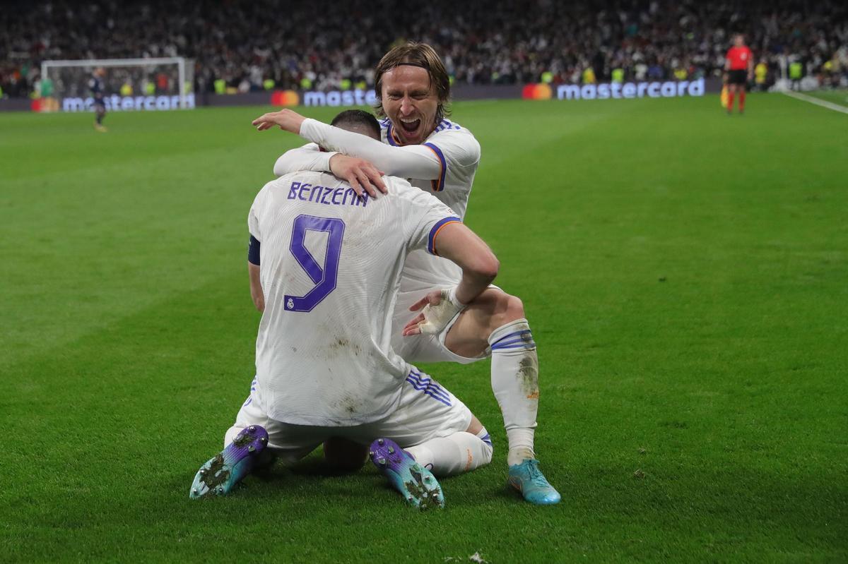 MADRID, 09/03/2022.- El delantero francés del Real Madrid Karim Benzema (de espaldas) celebra con Luka Modric el pase del equipo blanco a los cuartos de final de la Liga de Campeones tras derrotar al PSG en el encuentro disputado hoy miércoles en el estadio Santiago Bernabéu, en Madrid. EFE/Juanjo Martín.