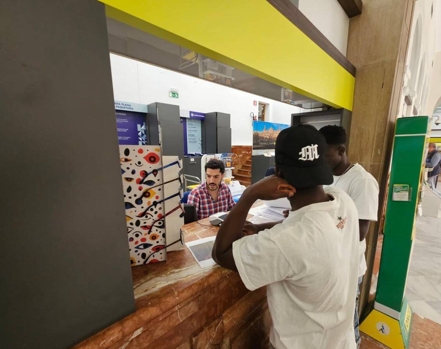 Dos usuarios son atendidos en una ventanilla de Correos. | CORREOS