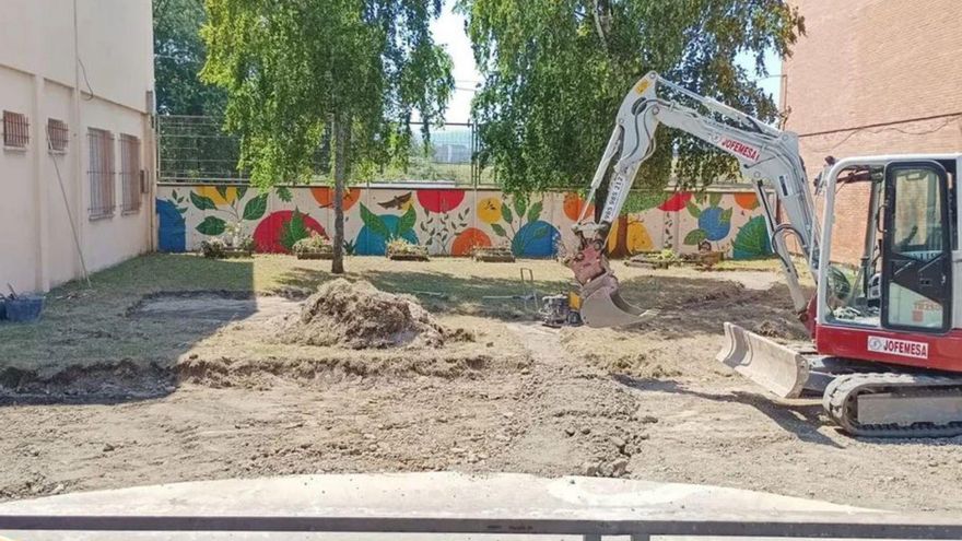 Trabajos en el patio a renaturalizar en la escuela infantil Miguel Hernández, con el nuevo mural al fondo.