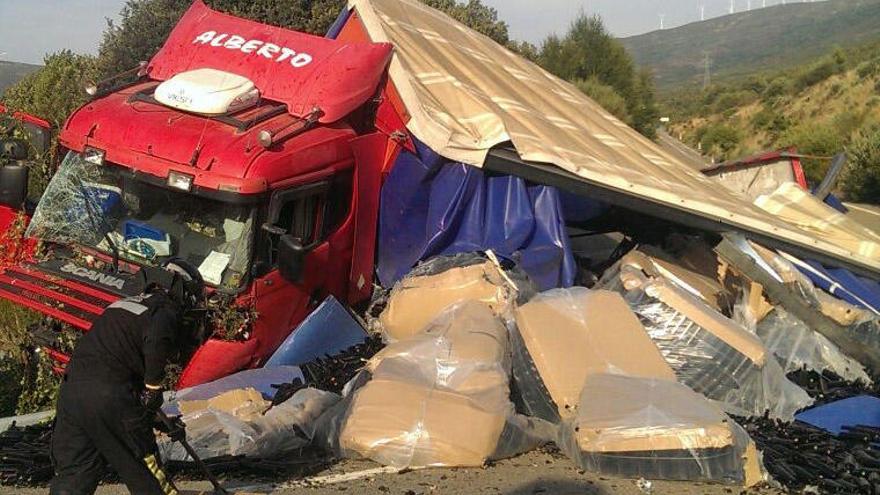 El camión, con la mercancía esparcida en la carretera tras el vuelco