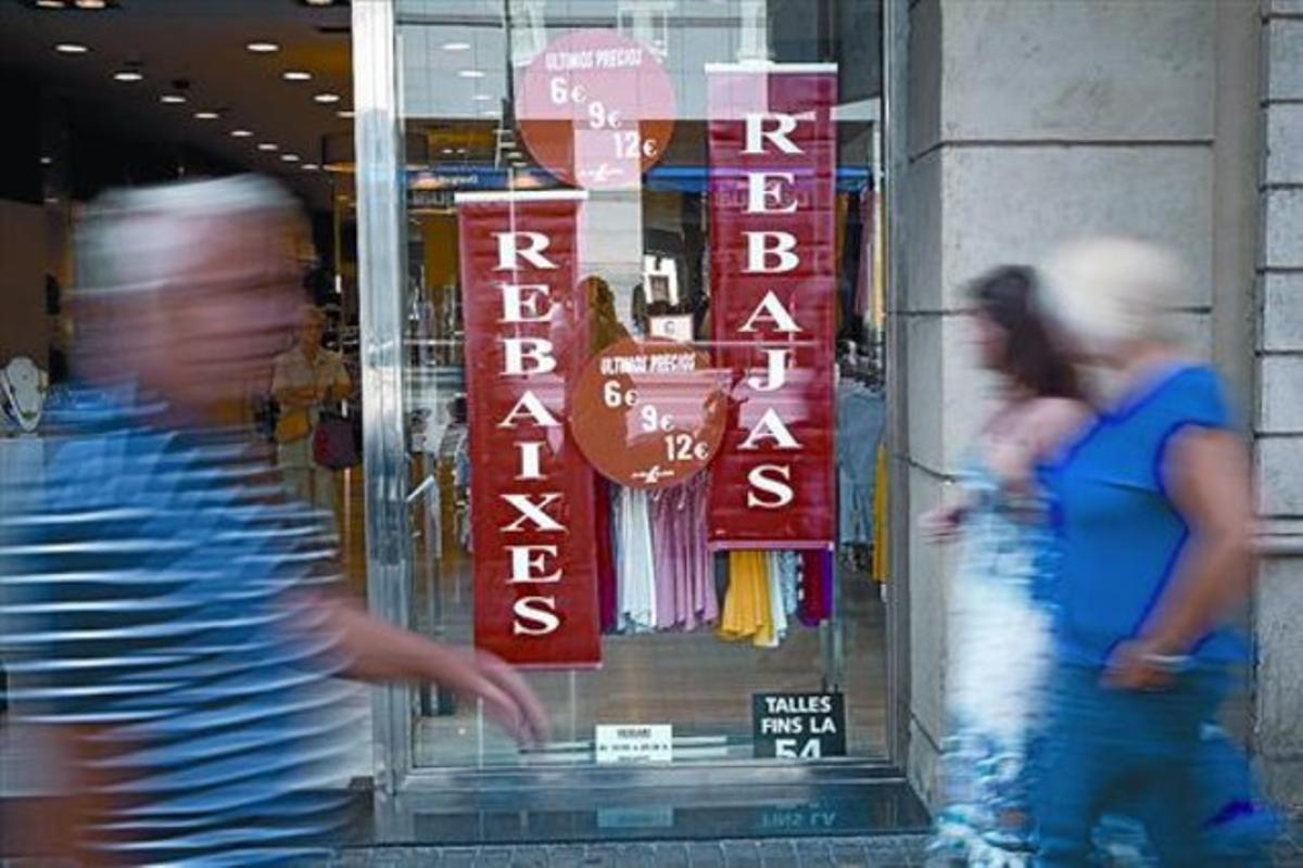 Transeünts passen, dissabte passat, davant els cartells de rebaixes d’un aparador del carrer de Pelai, a Barcelona. Transeünts passen, dissabte passat, davant els cartells de rebaixes d’un aparador del carrer de Pelai, a Barcelona.