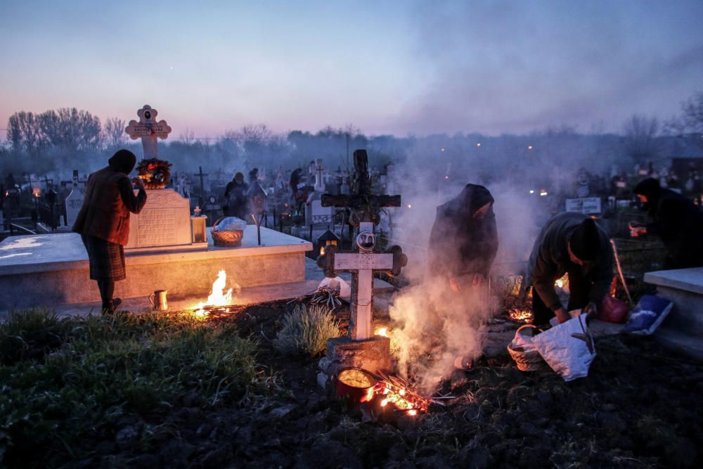Familiares prenden hogueras y queman incienso en el cementerio donde descansan los restos de sus allegados en Bucarest, Rumanía.