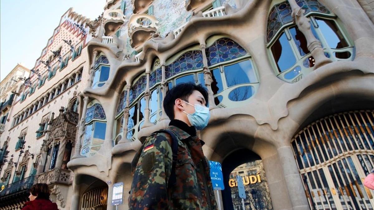 Un turista con mascarilla para evitar el contagio por coronavirus, frente a la Casa Batlló, en Barcelona