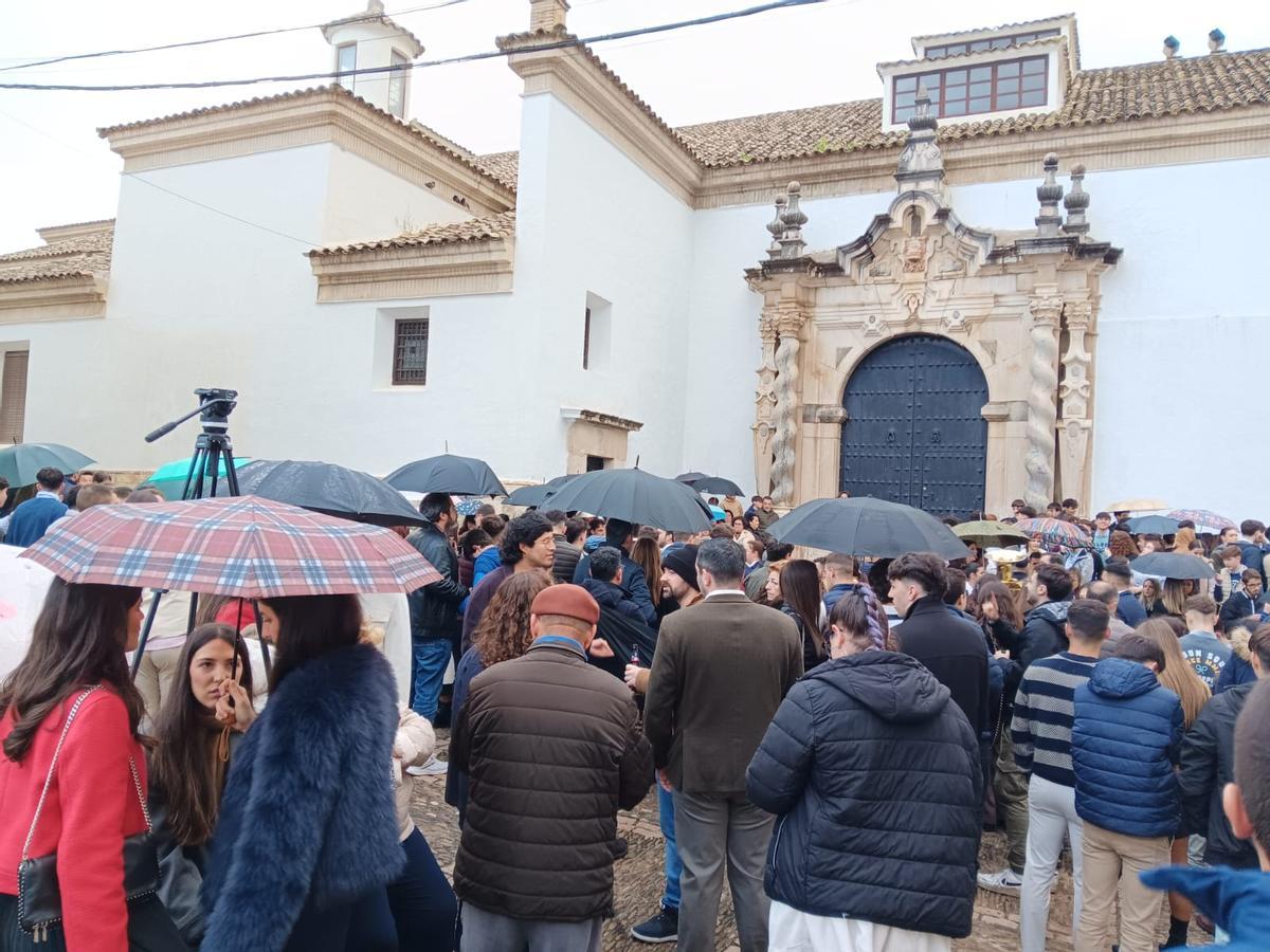 Las personas esperan bajo los paraguas la salida de la hermandad del Preso de Cabra.