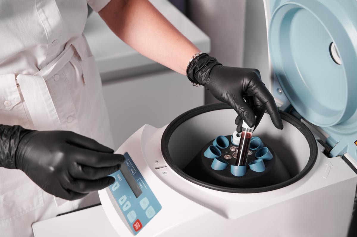 Researcher putting test tube into laboratory centrifuge.