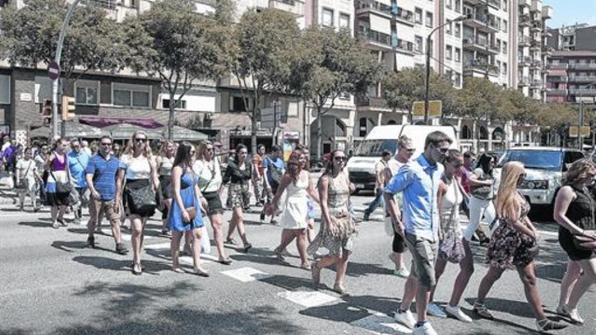 Unos excursionistas cruzan en grupo la calle de Aragó tras dejar  los autocares.