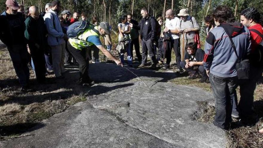 El arqueólogo Xurxo Constela muestra unos petroglifos, ayer, durante la ruta por Monte Penide.  // J. Lores