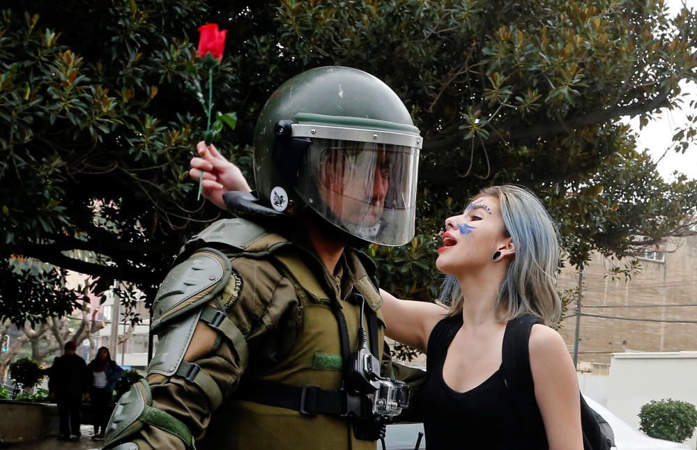 Un manifestante sujeta una rosa y grita slogans frente a un policía antidisturbios durante una marcha no autorizada promovida por estudiantes de secundaria en Valparaíso, Chile.