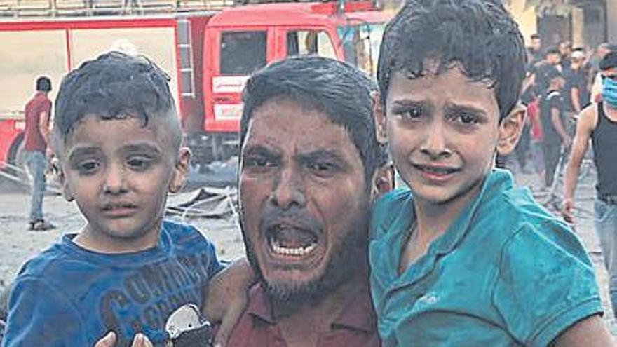 Un hombre lleva en brazos a dos niños tras un bombardeo
