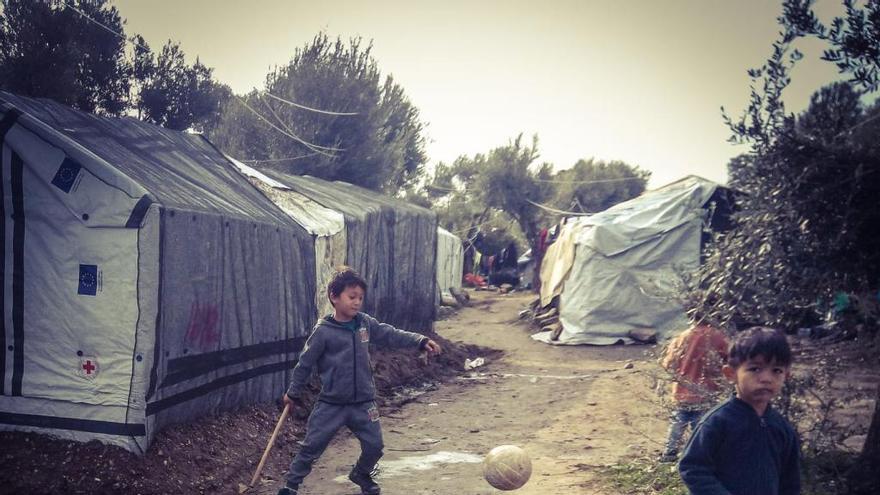Un niño mira a la cámara mientras otro juega con un balón en Moria, también en Grecia.