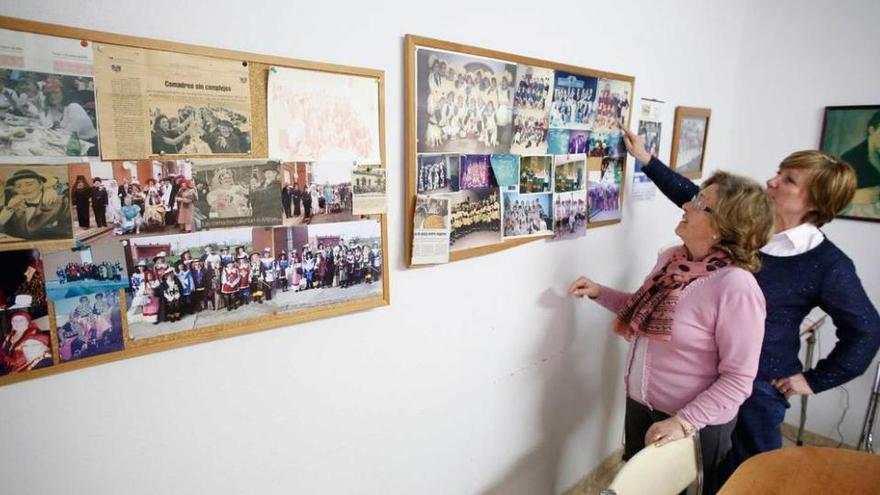 Remedios García Bermúdez y Cristina Martín, presidenta y secretaria de la Asociación de Amas de Casa de San Balandrán, respectivamente, contemplan un tablón con fotografías del colectivo.