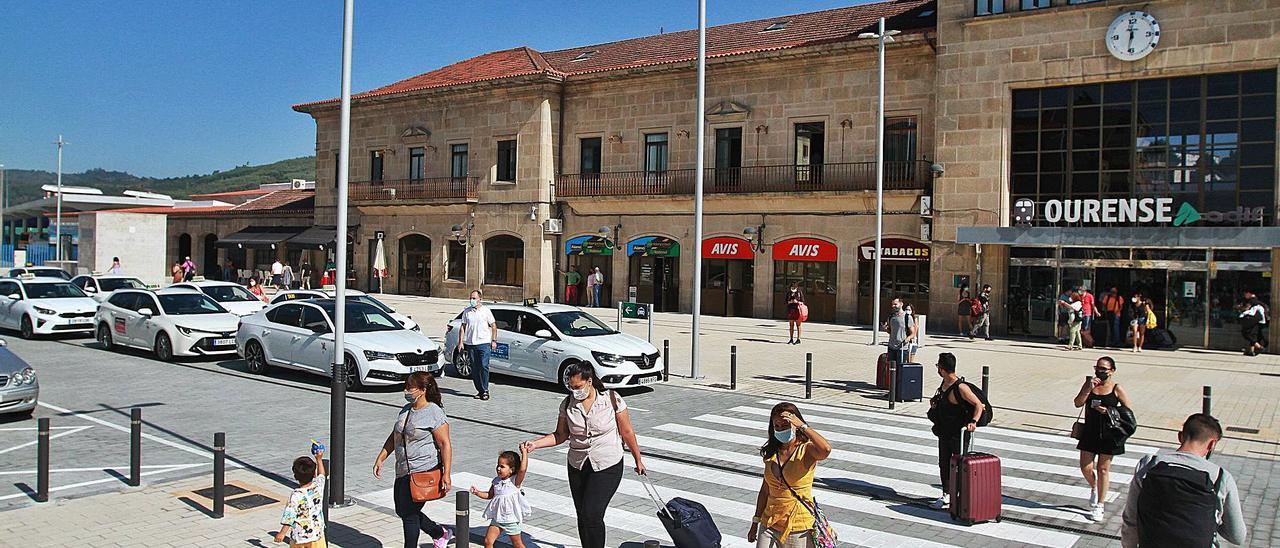 Usuarios de la estación recién llegados a Ourense, con los taxis esperando al sol.   // IÑAKI OSORIO