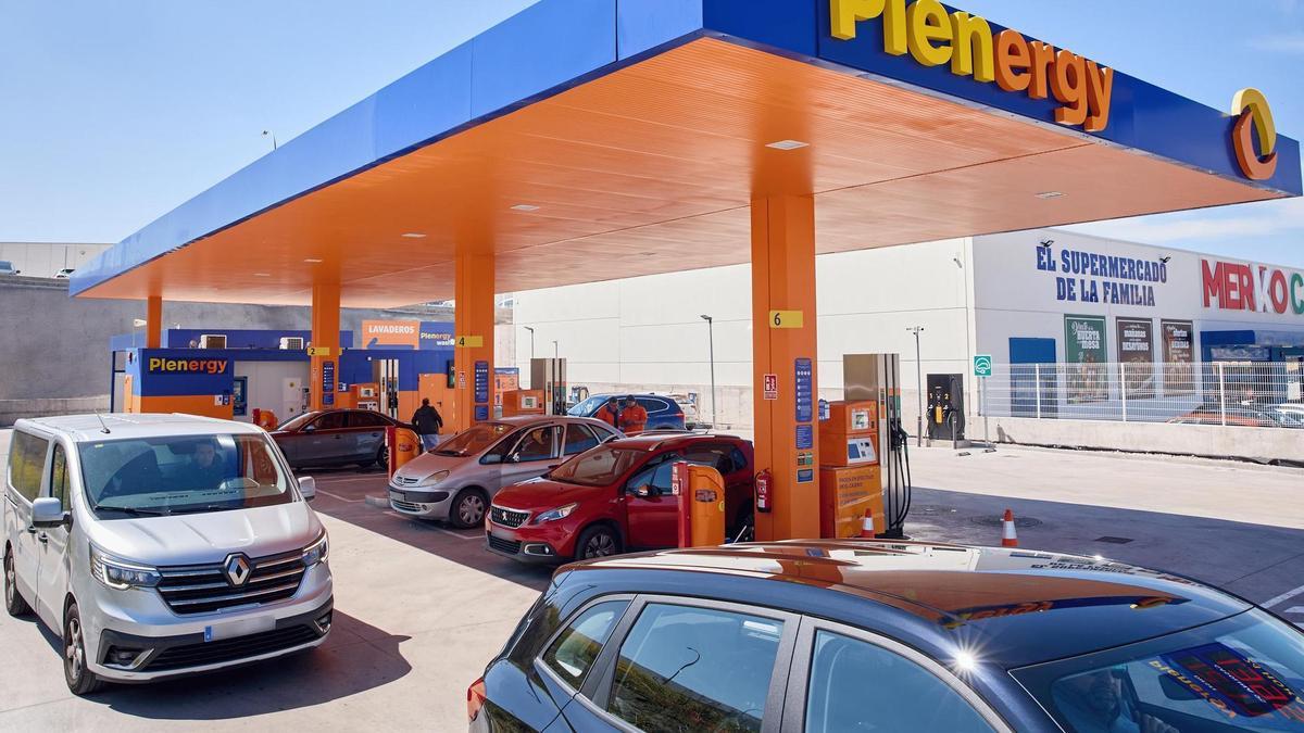 Coches repostando en una gasolinera de bajo precio.