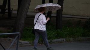 Archivo - Una mujer se protege de la lluvia con un paraguas, a 8 de junio de 2024, en Madrid (España)