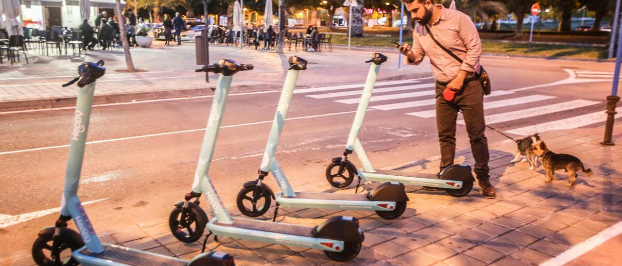 Un hombre fotografía los patinetes que se alquilan en Alicante