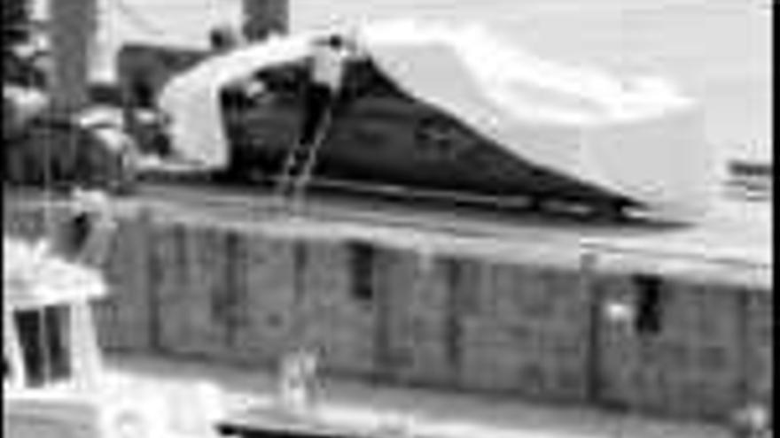 Un vigilante tapa con una lona el submarino, ayer por la tarde en unos astilleros de Meira (Moaña). / josé lores