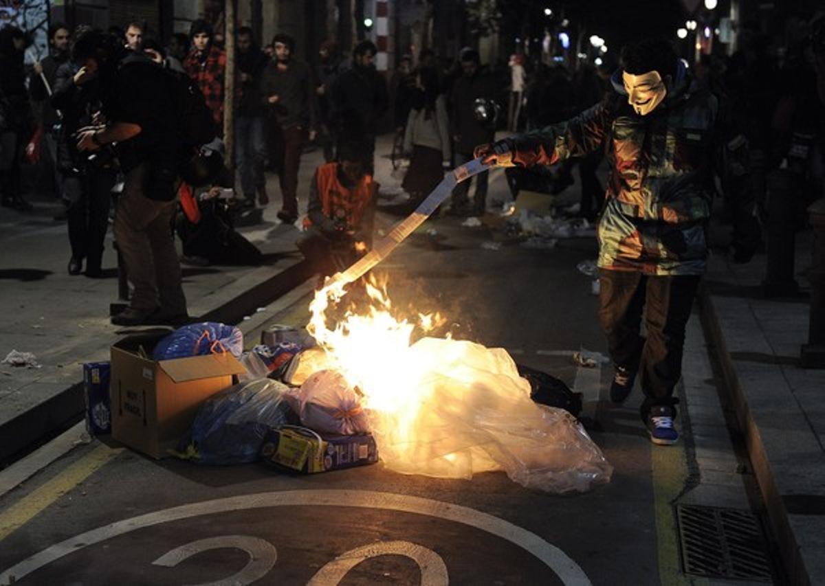 Un manifestant de suport a Gamonal cala foc a un munt d’escombraries. AFP / JOSEP LAGO